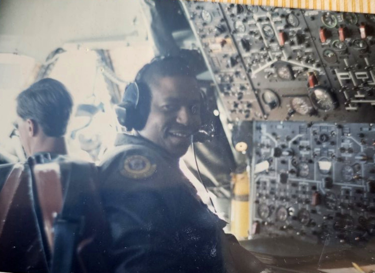 David Grey at the controls in the cockpit, headset on, mid flight deck